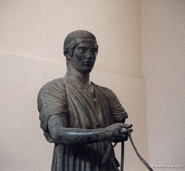 6037.jpg - 6037: Bronze statue of a charioteer belonging to a quadriga. Dedication of the Syracusean Polyzalos, brother of the tyrants Gelo and Hiero. Masterpiece of an unknown artist (about 478 BC). Archaeological Museum, Delphi.