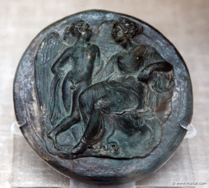 8323.jpg - 8323: Bronze mirror cover: Aphrodite seated on a rock accompanied by Eros. Greek c. 325-250 BC. British Museum, London.